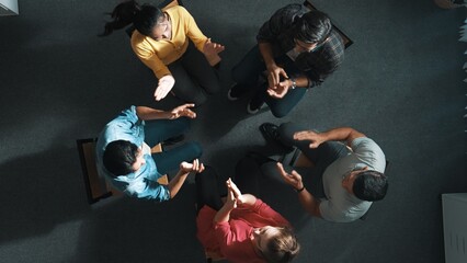 Top down aerial view of business people clap hands together to celebrate successful project while...