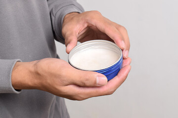 Man's hand holding pomade or waxe for hair styling isolated on white background
