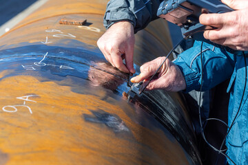 Inspector is testing to weld of pipe with ultrasonic test method. Ultrasonic testing is often performed on steel and other metals and alloys.