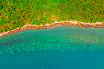 Lush jungle on a remote tropical island is fringed by a coral reef in Islands coast