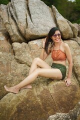 asian women in bikini sitting on the rock near the beach