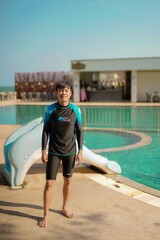 Obraz premium asian man standing in swimming pool with dolphin slider