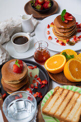 Breakfast table full of food brunch pancakes, bread and fruit