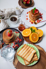 Breakfast table full of food brunch pancakes, bread and fruit