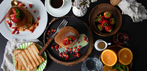 Breakfast table full of food brunch pancakes, bread and fruit