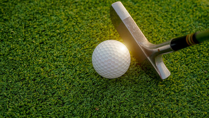 Golf ball and golf club on green in the evening golf course with sunshine.