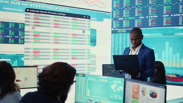 Chief financial officer studying capital funds and revenue data on big screen, verifying annual reports and budget allocation for a project. Looking for ways to increase profit. Camera B.