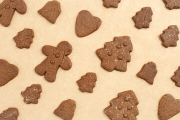 Christmas gingerbread cookies or biscuits on baking paper background. Top view minimal pattern, aesthetic flat lay from homemade festive sweet food, traditional bakery different shapes, new year