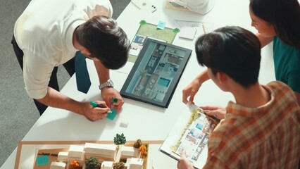 Top down view of manager pointing at house model and explain building design. Aerial view of...