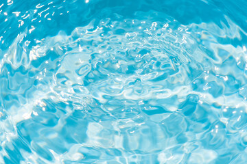 Blue water with ripples on the surface. Defocus blurred transparent blue colored clear calm water surface texture with splashes and bubbles. Water waves with shining pattern texture background.