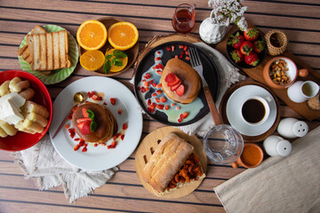 Breakfast table full of food brunch pancakes, bread and fruit