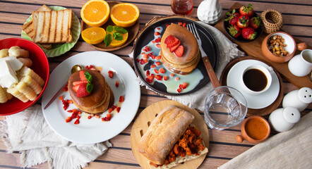 Breakfast table full of food brunch pancakes, bread and fruit
