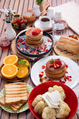 Breakfast table full of food brunch pancakes, bread and fruit