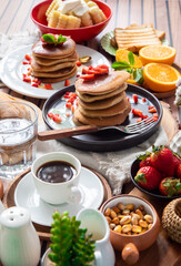 Breakfast table full of food brunch pancakes, bread and fruit