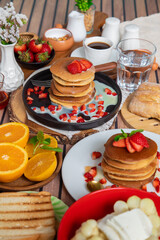 Breakfast table full of food brunch pancakes, bread and fruit