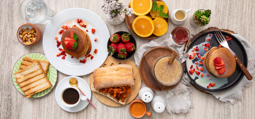 Breakfast table full of food brunch pancakes, bread and fruit