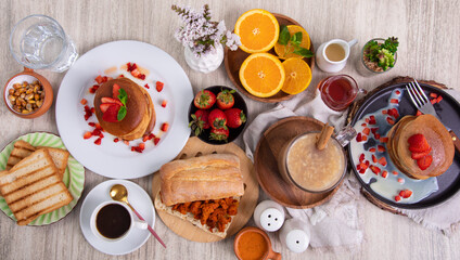 Breakfast table full of food brunch pancakes, bread and fruit
