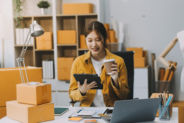 Asian SME business women use laptop computer checking customer order online shipping boxes at home....