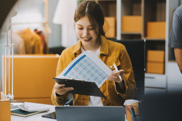 Asian SME business women use laptop computer checking customer order online shipping boxes at home....