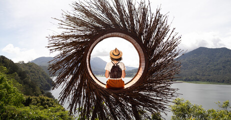 Female traveler contemplating nature sitting in straw nest looking at lake view in Munduk, Bali....