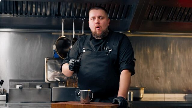 in a professional kitchen chef in a black jacket tastes freshly prepared French fries