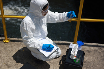 Scientists biologists or researchers in protective suits taking water samples from wastewater from...