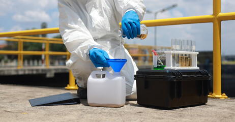 Scientists biologists or researchers in protective suits taking water samples from wastewater from...
