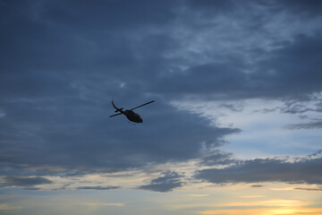 Photos of Military Helicopter flying against sunset.Flying a helicopter in the blue sunny sky