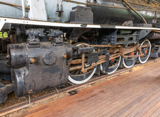 Naklejka premium An old steam locomotive no longer in use and showing cylinders, pistons and the massive drive wheels with rusting connecting rods in detail as the locomotive stands at a siding in South Africa.