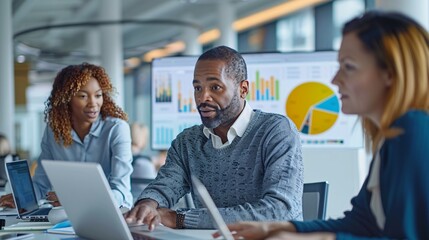 A corporate team working together in an open-plan office, analyzing financial data on laptops and digital screens