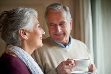 Senior couple, tea and window in home for relax, love and drink for married man and woman. Living...