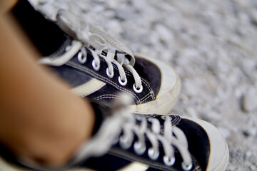 Obraz premium Two feet from a person wearing casual black-white shoes on the white-yellow-sulphuric gravel ground.