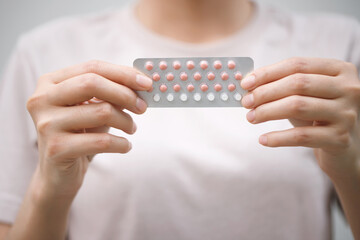 Woman hands opening birth control pills in hand. eating Contraceptive pill. Contraception reduces...