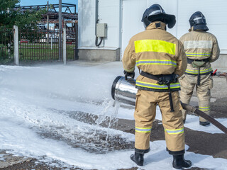 Firefighters in protective clothing use a foam generator to supply foam to extinguish the fire....