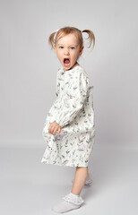 Studio shot of a little girl shouting with anger, standing on a white background