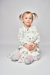 Little girl with white bunny on a white background with copy space. Portrait of beautiful little girl hugging her rabbit toy
