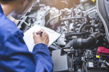 Auto check, car service shop concept. Automobile repairman writing job checklist on clipboard,...