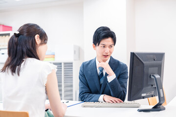 Obraz premium 不動産会社のカウンターで相談をする若い女性