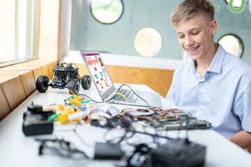 Blonde hair schoolboy in blue shirt watching motherboard while considering and smile in STEM class....