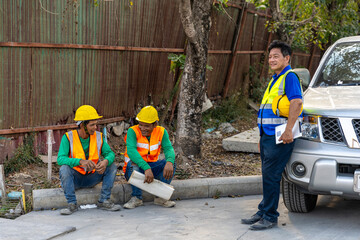 Team of civil engineers or workers in safety suits taking rest after a long day in a construction site waiting for the next assignment. Cooperation among construction workers in a factory.