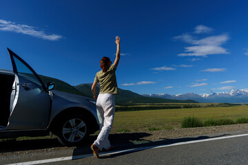 mature woman traveling by car stopped on the side of the road and admires the Altai mountains
