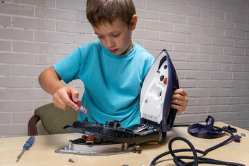 boy helps his mother. a funny master repairs an electric iron 