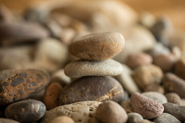 Pile of pebbles on the beach at sunset symbolizing a zen philosophy of peace and tranquility