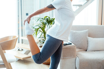 One woman doing fitness workout at home in indoor healthy leisure activity alone. Cozy apartment interior and people taking care of body. Healthy female people in pilates training routine lifestyle