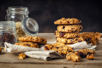 Stack of oat cookies with cranberry and raisins on a wooden table on a dark background