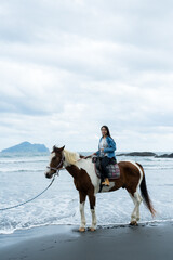 Tourist woman ride a horse beside the sea beach