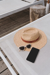 Flat lay of mobile phone with blank screen. Beautiful women's fashion summer accessories on sun...