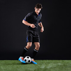 Fitness, ball and man soccer player on grass by black background for training, exercise or game. Sports, field and male athlete with equipment for football practice, workout or match in studio.