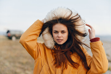 Young woman enjoying the windy field in orange coat and blowing hair, tranquil beauty of nature and...
