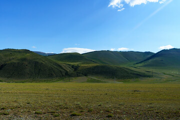 mountain slope in Altai against a background of clear blue sky and bright summer sun